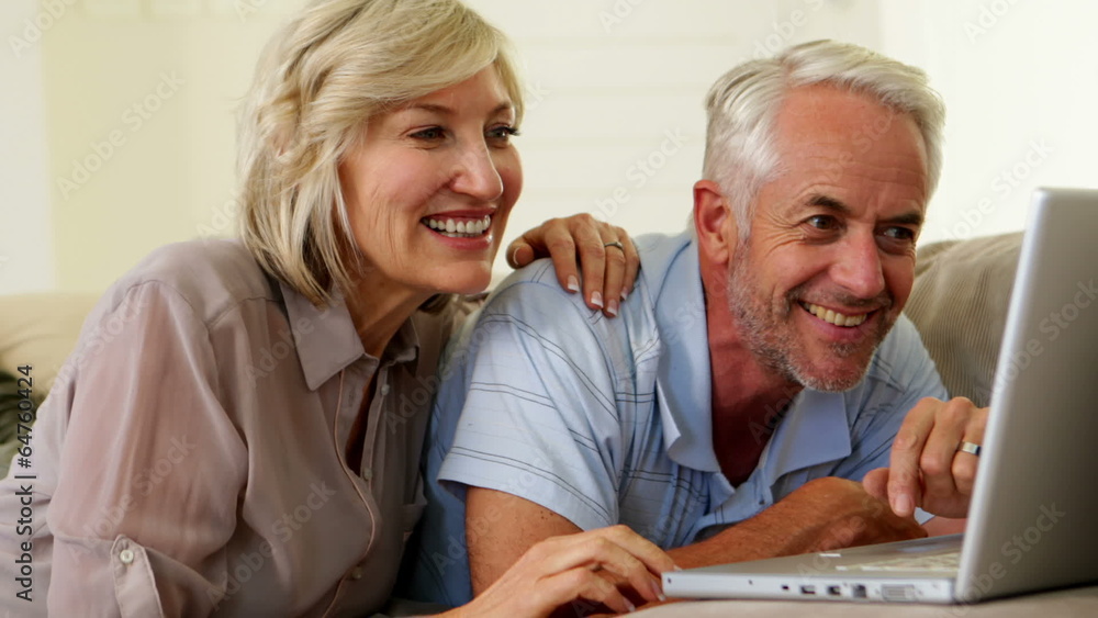Cheerful couple using laptop together Cheerful couple using laptop together