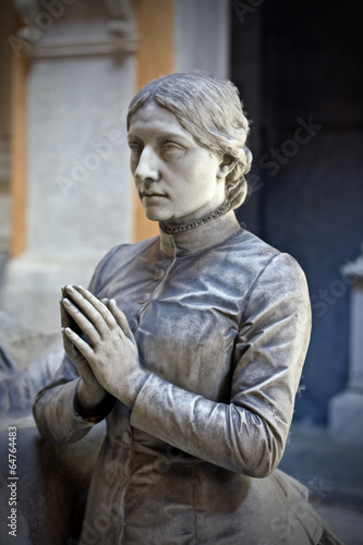 Statue of a woman praying on top of a tomb