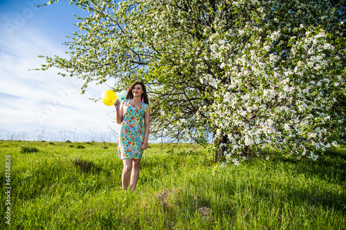 Girl with balloons in the apple orchard