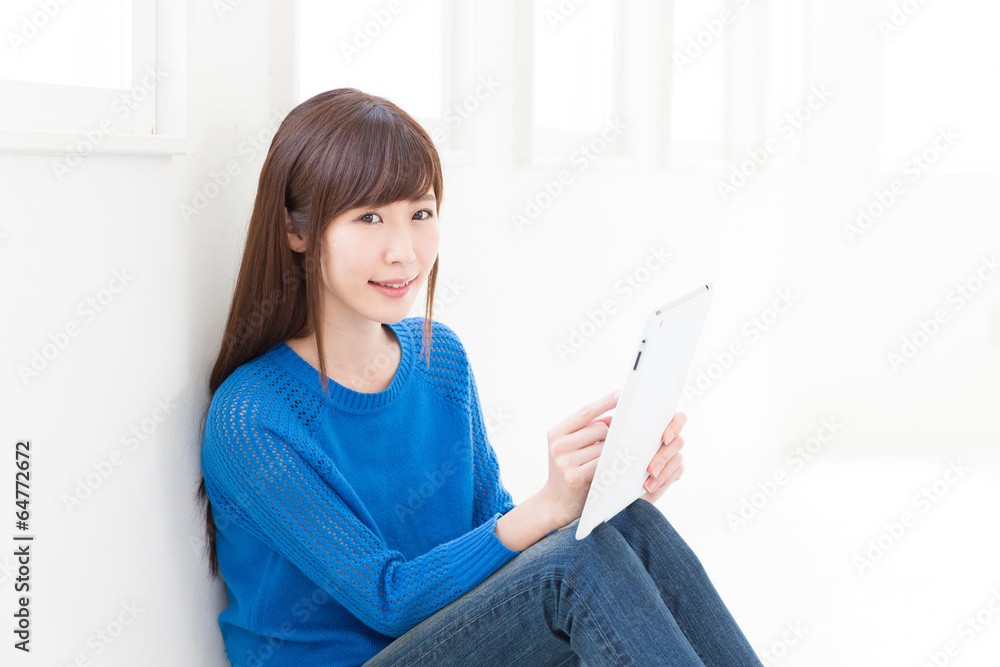 部屋でタブレットを見る女性