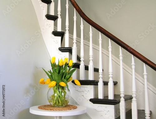 Fototapeta Naklejka Na Ścianę i Meble -  Yellow tulips on a round table beside heritage staircase