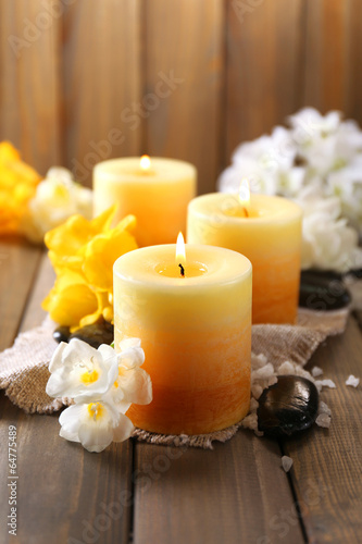 Beautiful candles with flowers on wooden background