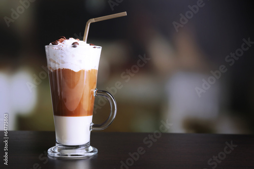 Glass of coffee on color wooden table, on dark background