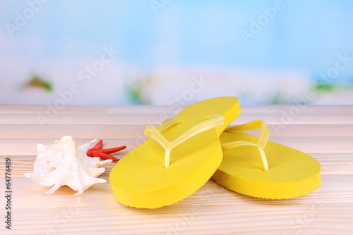 Bright flip-flops on wooden table, on nature background