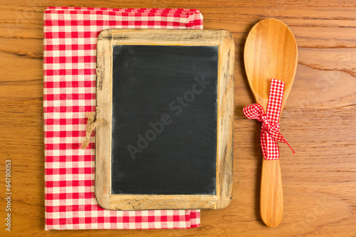 Chalkboard with wooden spoon on tabletop with tablecloth
