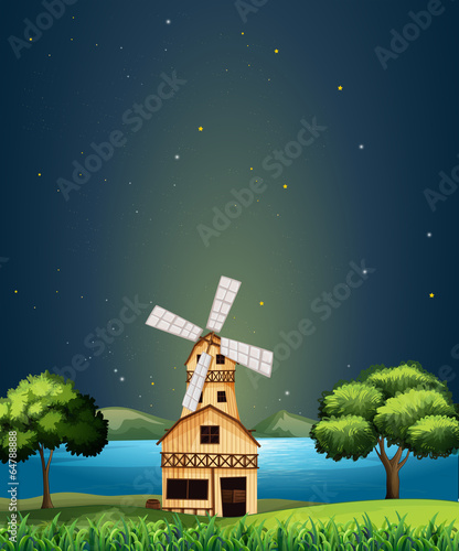 A wooden barnhouse at the river with a windmill