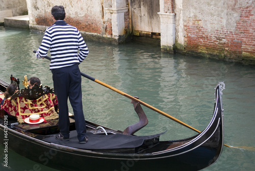 Fototapeta Gondolier are boating tourists in the typical venetian gondola