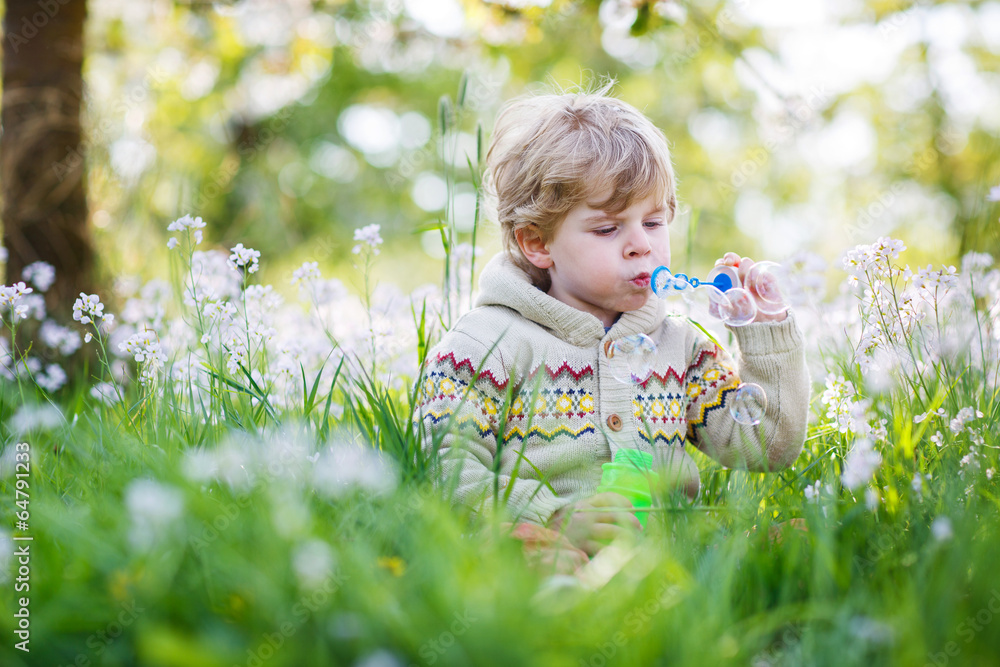 Happy little boy in spring garden with blooming white flowers Happy little boy in spring garden with blooming white flowers