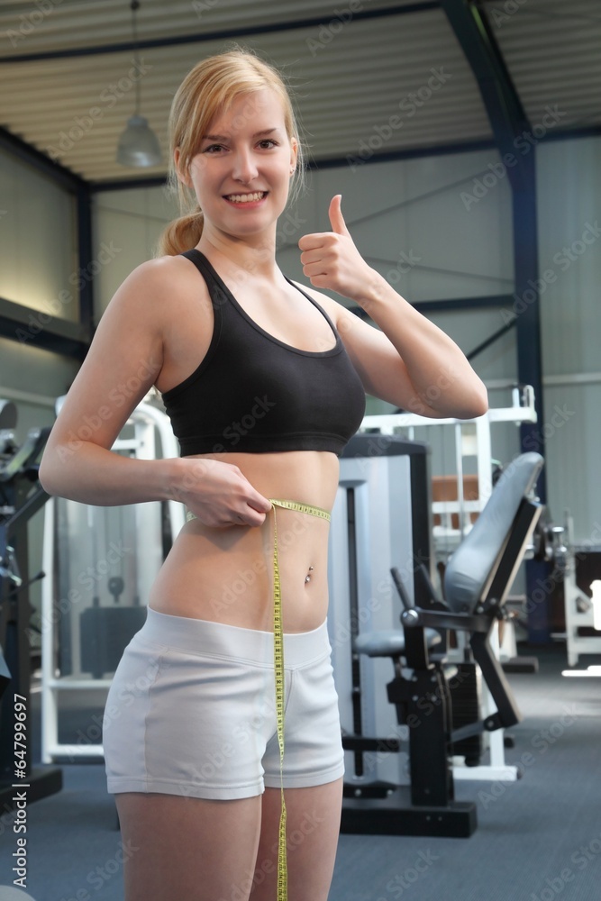 woman with measuring tape in a fitness studio - thumb up