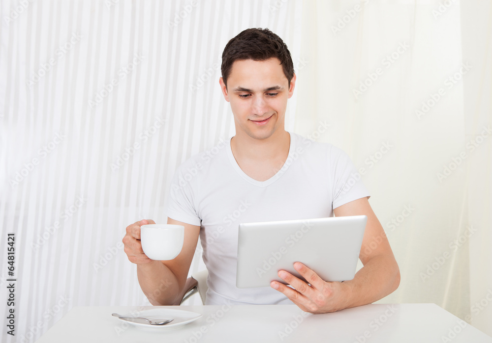 Man Using Digital Tablet While Having Coffee At Dining Table Man Using Digital Tablet While Having Coffee At Dining Table