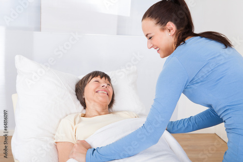 Caretaker Covering Senior Woman With Blanket