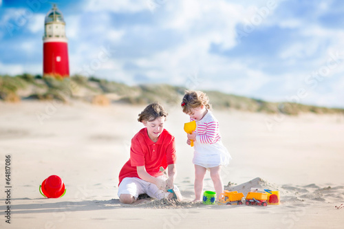 Huppy sibling playing on the beach next to lighthouse photo