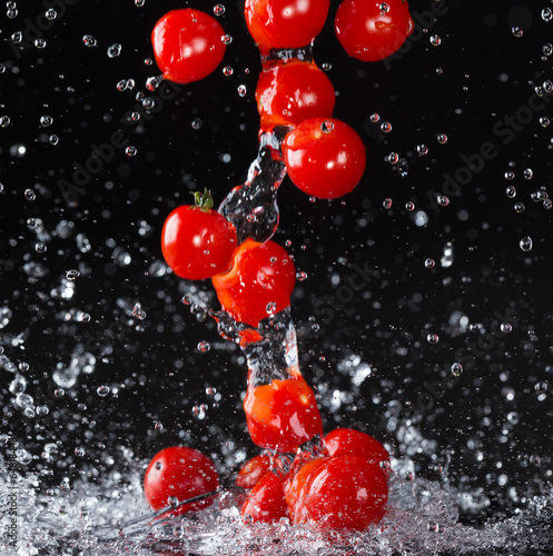 Cherry tomato in water splash on black background