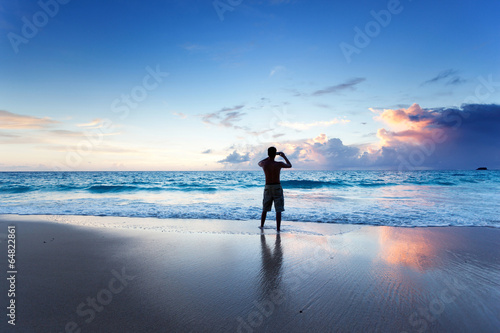 young man on the beach take photo on mobile phone