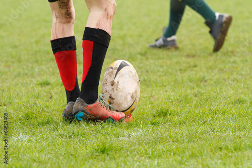 Dirty legs about to kick a rugby ball