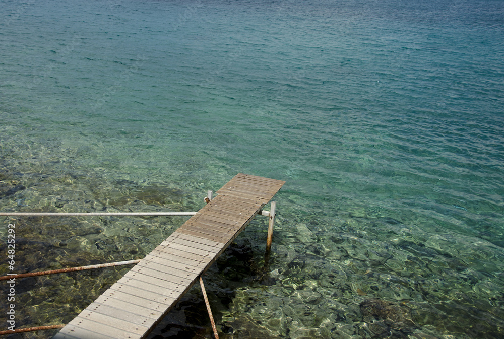 Empty pier on a lake with crystal clear tourquise waters,Greece. Empty pier on a lake with crystal clear tourquise waters,Greece.