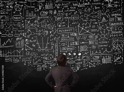 Businessman standing in front of drawn charts on a blackboard