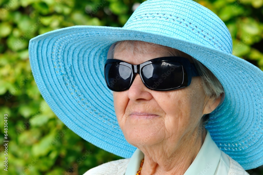 Senior woman in blue hat in garden.