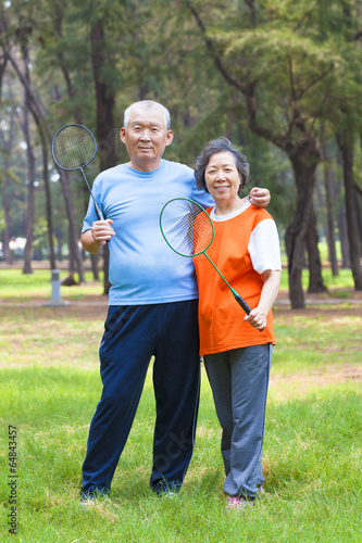 smiling senior couple holding badminton racket in the park