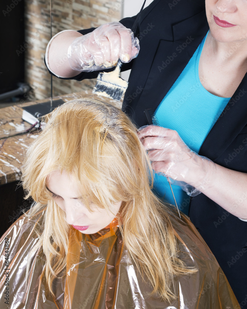 Fototapeta premium Hairdresser dyes long blond hair