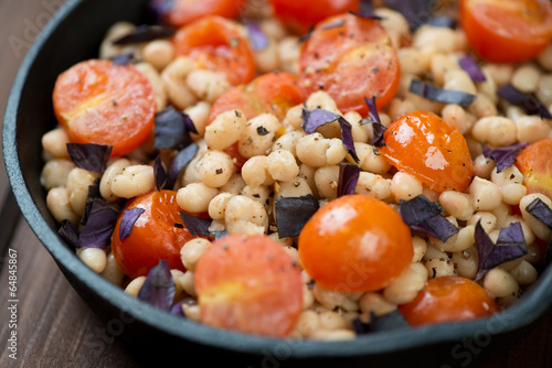 Roasted cherry tomatoes, white beans and basil, close-up