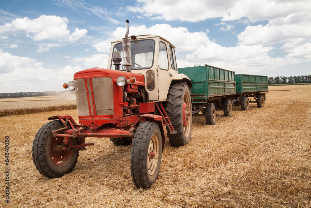 Obraz premium old tractor in field, against a cloudy sky