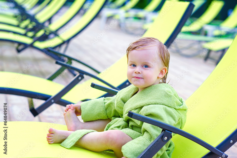 Cute toddler sitting on a lounge chair in the bathrobe Cute toddler sitting on a lounge chair in the bathrobe