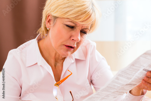 Seniorin liest mit Altersweitsichtigkeit Beipackzettel 