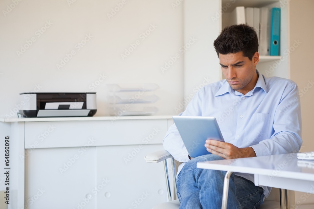 Casual businessman using his tablet at his desk