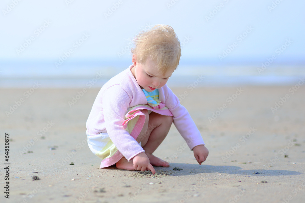 Adorable toddler girl in beautiful white dress playing on beach Adorable toddler girl in beautiful white dress playing on beach