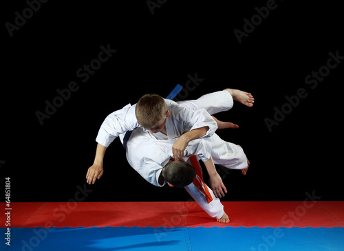 Two young athletes in the sharp drop perform judo throw