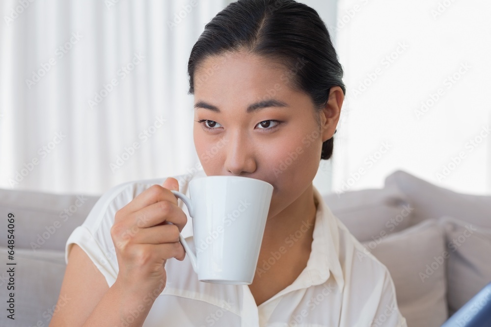 Smiling woman sitting on couch having coffee Smiling woman sitting on couch having coffee