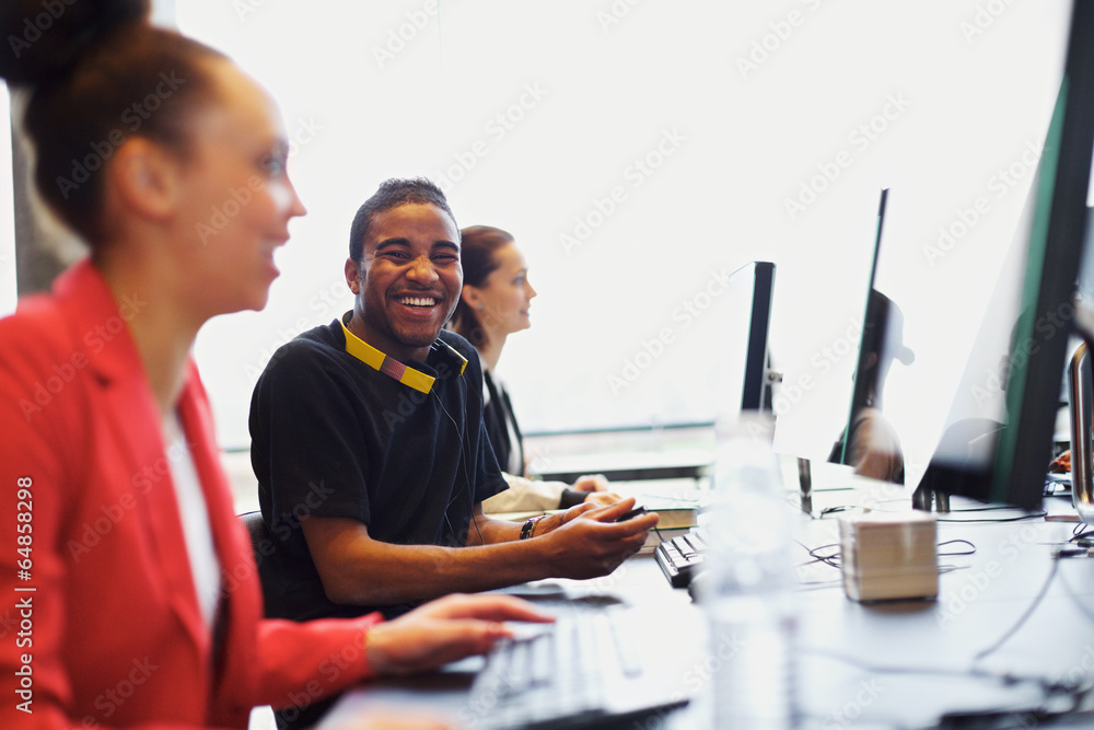 Young student in class with other students working on computers Young student in class with other students working on computers