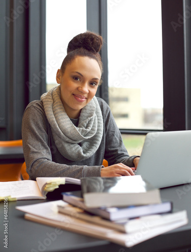Young woman studying at a desk using books and laptop