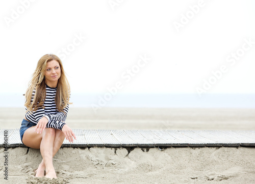 Young woman sitting at the beach thinking