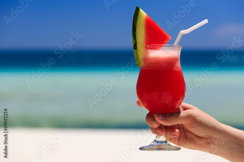 hand holding watermelon cocktail on the beach