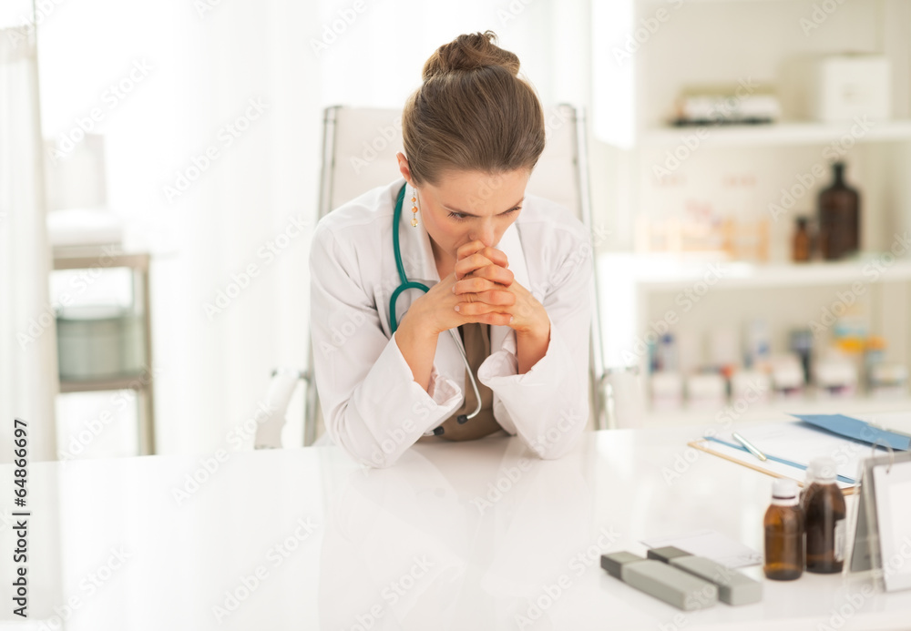 Concerned medical doctor woman sitting in office Concerned medical doctor woman sitting in office