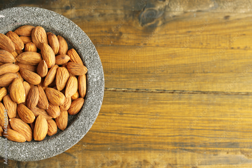 Almonds in bowl on color wooden background Almonds in bowl on color wooden background