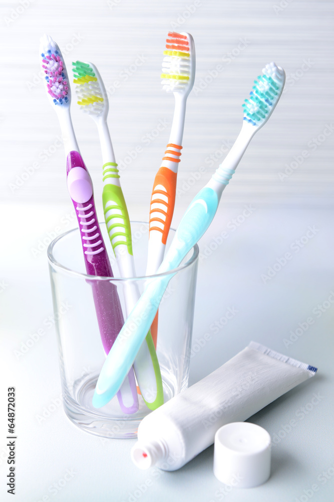 Toothbrushes in glass on table on light background Toothbrushes in glass on table on light background