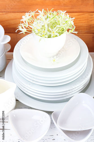 Different tableware on shelf, on wooden background