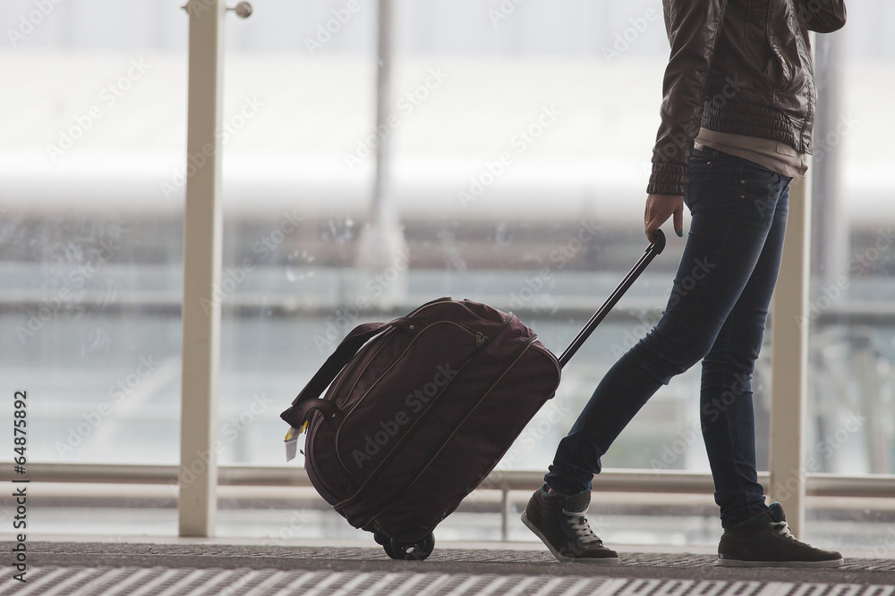 Fototapeta premium Kobieta niesie Twój bagaż na terminalu lotniska