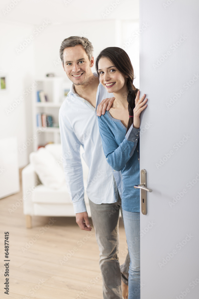 Cheerful couple inviting people to enter in home Cheerful couple inviting people to enter in home