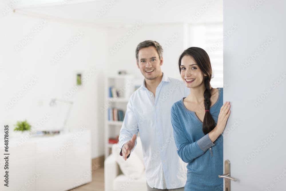 Cheerful couple inviting people to enter in home Cheerful couple inviting people to enter in home