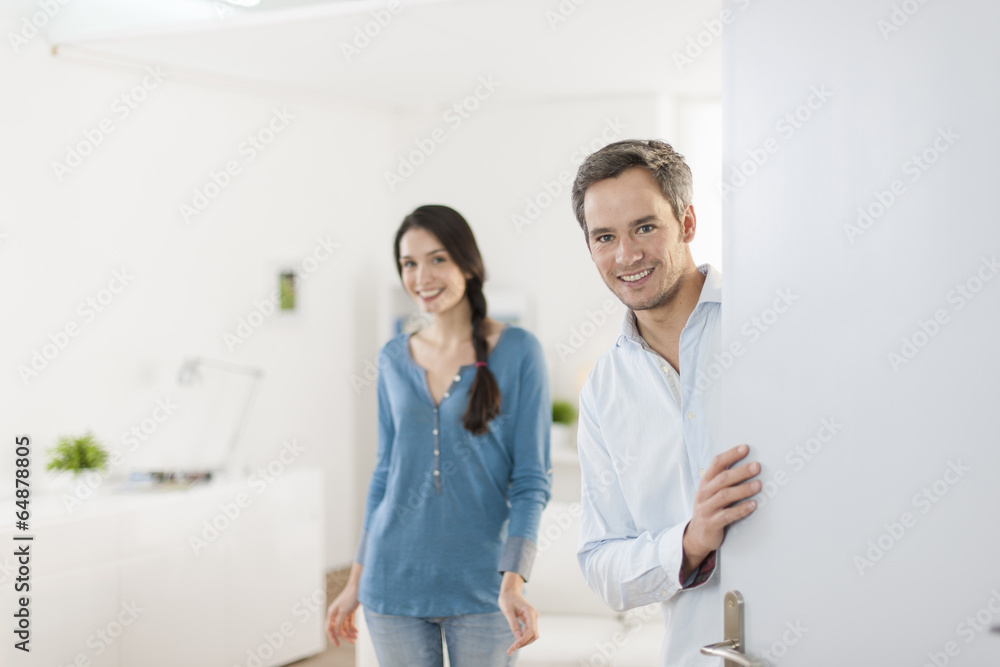 Fototapeta premium Cheerful couple inviting people to enter in home