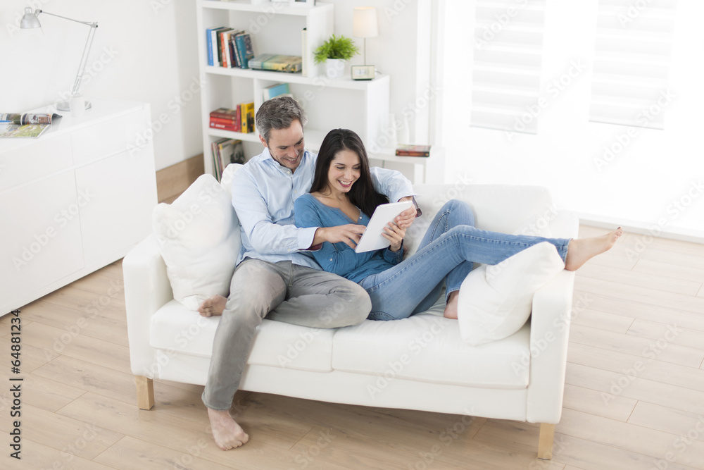 cheerful couple using digital tablet in sofa at home cheerful couple using digital tablet in sofa at home
