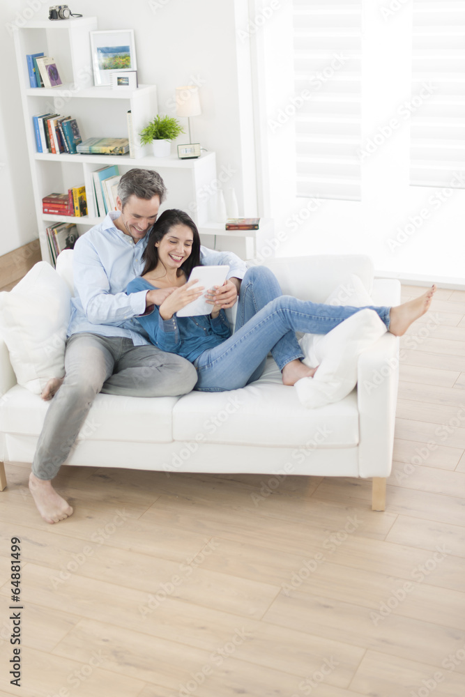 cheerful couple using digital tablet in sofa at home