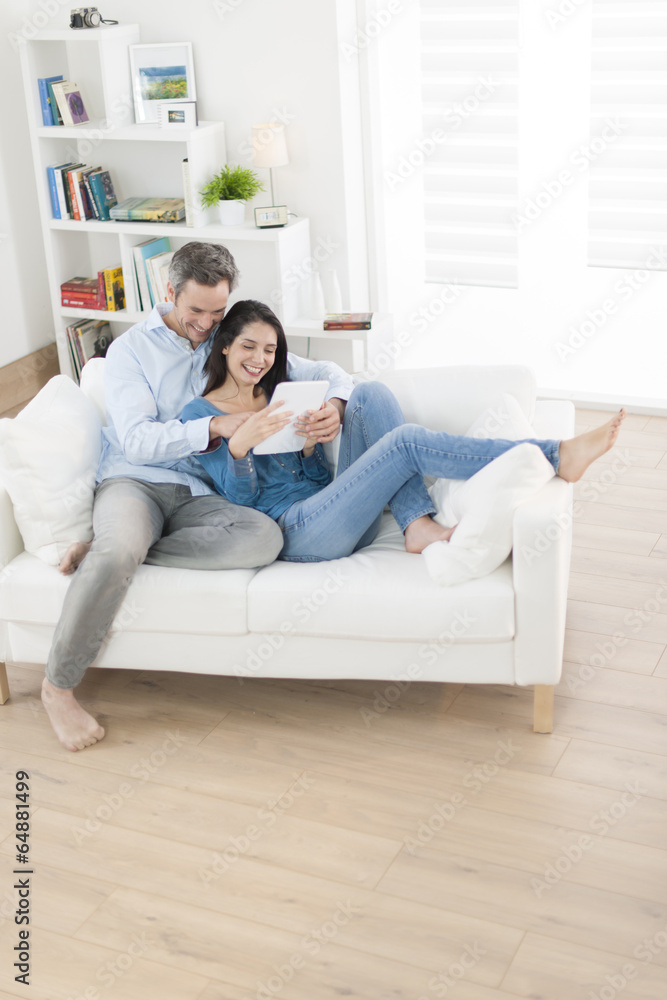 cheerful couple using digital tablet in sofa at home cheerful couple using digital tablet in sofa at home