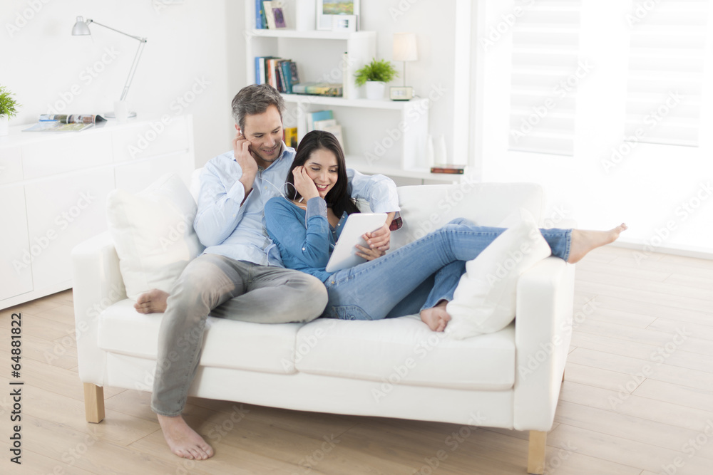 cheerful couple sharing music on digital tablet in sofa at home cheerful couple sharing music on digital tablet in sofa at home