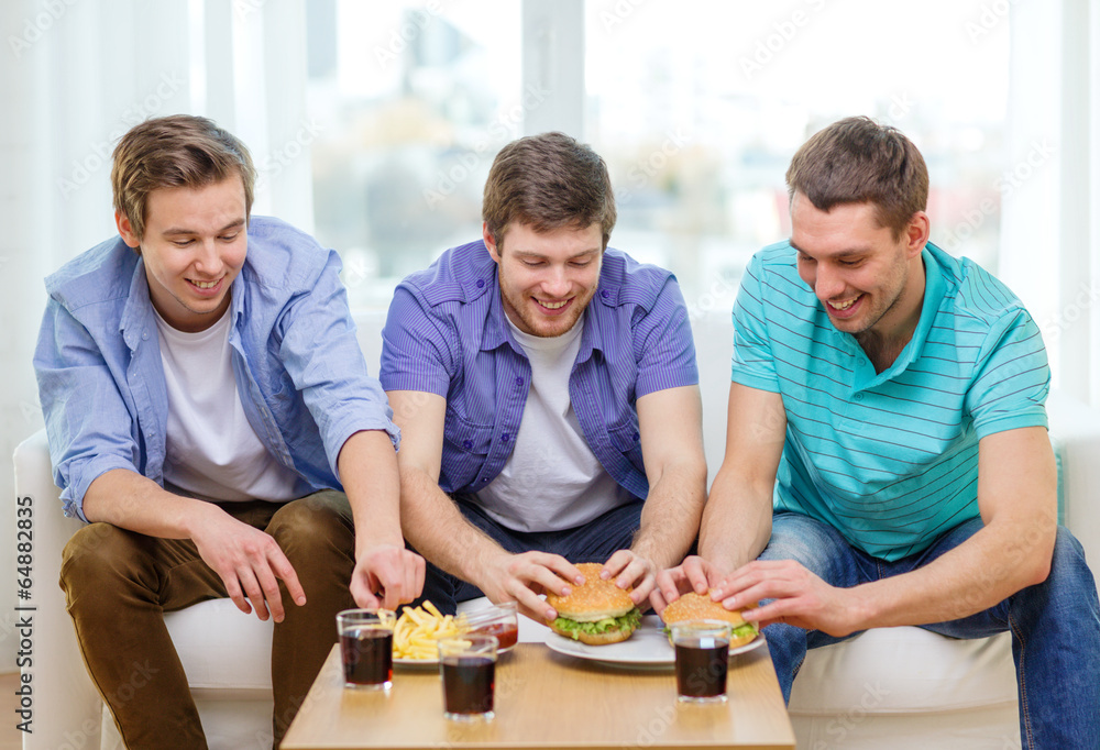 smiling friends with soda and hamburgers at home smiling friends with soda and hamburgers at home