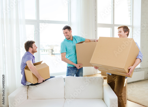 smiling male friends carrying boxes at new place © Syda Productions